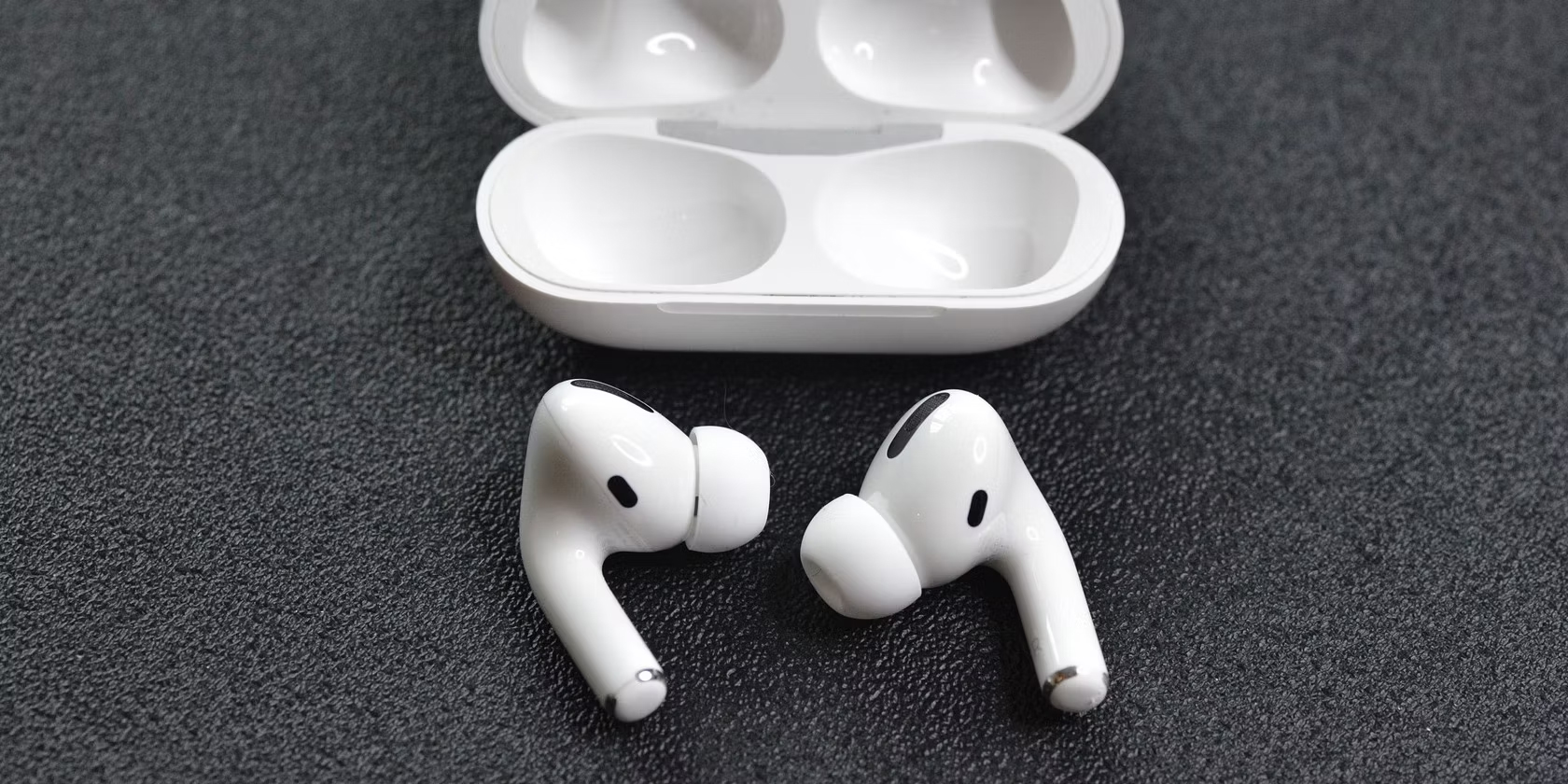 two-airpods-pro-and-its-charging-case-on-a-gray-background